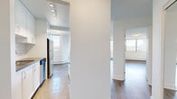Located on Erickson Drive in Burnaby, BC, this well-appointed one-bedroom, one-bathroom unit offers a thoughtfully designed layout with modern updates throughout. Light hardwood-style flooring flows seamlessly across the living spaces, complementing the clean white walls and textured ceilings that give the unit a bright, airy feel.

The open-concept kitchen and living area serves as the heart of the home. The kitchen features white shaker-style cabinetry extending to the ceiling for ample storage, a classic white subway tile backsplash, a stainless steel refrigerator, and a peninsula with a dark quartz countertop — ideal for casual dining or entertaining. The living area is bathed in natural light courtesy of expansive floor-to-ceiling windows that frame breathtaking mountain and treetop views, with access to an outdoor balcony.

The generously sized primary bedroom also benefits from large windows with mountain views, light flooring, and a mirrored sliding-door closet offering practical storage. Baseboard heating runs throughout the unit for efficient, consistent warmth.

The bathroom is finished to a high standard, showcasing a dark wood vanity with a white quartz countertop, a large mirror, subway tile surround on the tub-shower combination, and tile flooring — creating a clean, contemporary aesthetic throughout.