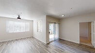 This well-appointed single-floor unit offers a clean, contemporary design throughout. The open-concept living area is finished with light wood-look flooring, neutral-toned walls, and a textured ceiling, creating a bright and welcoming atmosphere. A ceiling fan adds functionality, while multiple windows dressed with horizontal blinds invite abundant natural light. A sliding glass door with vertical blinds connects the living space directly to an outdoor area, extending the sense of openness.

The kitchen is a standout feature, showcasing white shaker-style cabinetry, gray stone-look countertops, and a classic white subway tile backsplash. Stainless steel appliances — including a refrigerator, range, and over-the-range microwave — complement the modern aesthetic. A peninsula with additional counter space provides a natural transition between the kitchen and the main living area, ideal for both meal preparation and casual dining.

The bathroom is thoughtfully finished with matching wood-look tile flooring, a wide vanity featuring white cabinetry and a gray countertop, a large mirror with overhead lighting, and a full tub-shower combination. The overall design maintains a consistent, cohesive palette of whites and grays, lending the space a fresh, move-in-ready appeal.