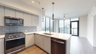 Located in the heart of Midtown Atlanta, this modern 2-bedroom, 5-bathroom residence offers a sleek, contemporary design with an open, efficient layout. Floor-to-ceiling windows flood every room with natural light and frame stunning panoramic views of the Atlanta skyline, including iconic landmarks and the vibrant cityscape below.

The kitchen is a standout feature, showcasing glossy gray cabinetry, a gray subway tile backsplash, quartz countertops, and a peninsula island with an undermount sink. Stainless steel appliances — including a gas range, built-in microwave, and French door refrigerator — complete the space. Sculptural pendant lights and track lighting add a designer touch, while the open layout connects seamlessly to the living area.

The bedrooms feature dark hardwood flooring and expansive floor-to-ceiling windows with Atlanta city views. A dedicated closet provides practical storage. The bathrooms are elegantly finished with large-format tile, glass-enclosed walk-in showers featuring mosaic tile accents, linear drains, and built-in shelving for added convenience.

A hallway with a stacked in-unit washer and dryer adds everyday functionality. Throughout the residence, clean white walls, wood-tone flooring, and modern fixtures create a cohesive, sophisticated urban living environment.