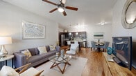 This single-story, 2-bedroom, 3-bathroom residence offers a thoughtfully designed open-concept layout that seamlessly connects the living, dining, and kitchen areas. Rich hardwood-style flooring flows throughout the main living spaces, complemented by neutral gray tones and elevated ceilings that create an airy, spacious feel. A ceiling fan anchors the living room, which features large windows that invite abundant natural light. The kitchen is a standout, boasting dark espresso cabinetry, granite-style countertops, a subway tile backsplash, stainless steel appliances, and a central island with bar seating — ideal for both casual dining and entertaining. The adjacent dining area comfortably accommodates a full table and chairs. The primary bedroom offers a generous footprint with hardwood-style floors, a dedicated closet, and an en-suite bathroom. The bathrooms are finished with dark wood vanities and granite-style countertops, with tub-shower combinations. A dedicated laundry room houses a full-size washer and dryer. The overall design balances modern aesthetics with functional living, making this a comfortable and well-equipped residence throughout.
