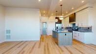 This well-appointed two-story home in Bozeman, Montana offers four bedrooms and two bathrooms across two floors. The main level features an open-concept layout where the kitchen, dining, and living areas flow seamlessly together. The kitchen is a standout, showcasing white shaker cabinetry, a bold tile backsplash, dark countertops, a central island with a light wood finish, stainless steel appliances, and stylish pendant lighting. Large windows in the dining nook flood the space with natural light and offer views of the surrounding neighborhood and Montana landscape. Light-toned hardwood flooring runs throughout the main level, adding warmth and continuity. Bedrooms are carpeted and bright, with generous windows and closet space. The primary bathroom impresses with a dual-sink vanity featuring light wood cabinetry and dark countertops, marble-style tile walls, a sliding glass shower enclosure, and elegant sconce lighting. The secondary bathroom mirrors this refined aesthetic with a tub-shower combo clad in marble-style tile, a single vanity, and clean modern fixtures. The upper floor provides additional bedroom space, maintaining the home's consistent, contemporary design throughout.