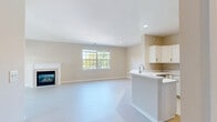 Located at 98 Waterside Drive in Wildwood, Missouri, this well-appointed one-bedroom, one-bathroom unit offers a comfortable and functional single-floor layout. The open-concept kitchen and living room serves as the heart of the home, featuring a cozy fireplace flanked by a large multi-pane window that frames pleasant tree-lined views. The kitchen is outfitted with crisp white cabinetry, stainless steel appliances including a gas range, built-in microwave, and refrigerator, as well as a peninsula with a white countertop that provides additional prep and dining space. Light hardwood-style flooring runs throughout the main living areas, contributing to a bright and airy atmosphere. The spacious bedroom features soft carpeting, a generously sized window offering natural light and outdoor views, and access to a dedicated walk-in closet equipped with wire shelving for organized storage. The full bathroom includes a combined tub and shower, a white vanity, and tile flooring. A dedicated laundry room with a full-size washer and dryer, tile flooring, and additional wire shelving adds everyday convenience. Neutral warm tones, clean finishes, and recessed lighting throughout the unit create a welcoming and move-in-ready environment.