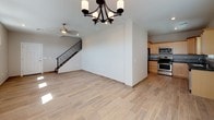 This two-story home is designed with a practical and cohesive aesthetic throughout. The main level features an open-concept living and dining area finished with wood-look tile flooring that flows seamlessly from room to room. A ceiling fan and chandelier provide overhead lighting, while a window along the front wall allows natural light to fill the space. A staircase with a black metal railing connects the main level to the upper floor.

The kitchen is outfitted with light maple cabinetry, dark countertops, a decorative tile backsplash, and a full suite of stainless steel appliances including a gas range, microwave, dishwasher, and refrigerator. Wood-look tile flooring continues throughout, and a window above the sink brings in additional natural light.

Upstairs, the carpeted bedrooms offer a comfortable, quiet atmosphere. Each room features neutral-toned walls, blinds-covered windows, and ceiling fans or light fixtures. One bedroom connects directly to a hallway bath. The bathrooms include wood-grain tile surrounds, a soaking tub, and a vanity with a stone-patterned countertop. A dedicated laundry area with a full-size washer and dryer completes the upper level.