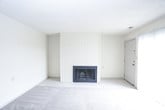 This single-floor residence offers a practical and comfortable layout with a neutral color palette throughout. The living area is finished with plush wall-to-wall carpeting and light-toned walls, creating a bright and welcoming atmosphere. A textured ceiling adds character to the space, while tile flooring transitions seamlessly from the living area into the kitchen. Natural light filters through a window fitted with horizontal blinds, enhancing the open feel of the room.

The kitchen is thoughtfully designed with warm wood-toned cabinetry providing ample storage space. Black appliances, including a refrigerator, electric range, over-the-range microwave, and dishwasher, offer a sleek contrast against the light tile flooring and countertops. Under-cabinet lighting adds functional illumination to the workspace.

The bedroom is generously sized, featuring the same plush carpeting found in the living area and a window that allows natural light to brighten the space. Textured ceilings are consistent throughout the home.

The bathroom is clean and functional, equipped with a full tub-shower combination unit in white, a toilet, and light tile flooring. The neutral tones throughout the home create a cohesive and move-in ready environment, making the space versatile for a variety of furnishing and décor styles.