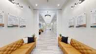 Located at 5101 Hollenbeck Dr in Perrysburg, Ohio, this impressive single-story clubhouse offers a generous and thoughtfully designed layout across a wide array of amenity spaces. The welcoming entryway features elegant tray ceilings, warm wall sconces, and light stone-look tile flooring that sets an upscale tone throughout. The main living area boasts soaring vaulted ceilings, light hardwood floors, a striking stone fireplace, and expansive windows that flood the room with natural light and provide views of the outdoor pool area. A second lounge space offers comfortable seating and a wall-mounted display. The open-concept dining, kitchen, and living area is outfitted with crisp white shaker cabinetry accented by gold hardware, quartz countertops, a classic subway tile backsplash, and stainless steel appliances. The adjacent dining area features a round wood table beneath tasteful wall art. The game room impresses with high ceilings, ping-pong, billiards, foosball, a fireplace, and ample lounge seating. A dedicated entertainment room with a projection screen and cinema-style ambiance completes the recreational offerings. The fitness center provides a well-equipped workout space with strength and cardio equipment, mirrors, and a convenience vending area. A sleek private office with designer wall art rounds out this exceptional space.