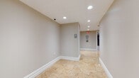 Located at 29 Linden in Hackensack, NJ, this single-floor common area is thoughtfully designed to serve residents with a clean, functional, and refined aesthetic. The space is finished with large-format stone-look tile flooring throughout the primary corridors, offering a polished and durable surface that lends an upscale feel to the utility-focused layout. Neutral warm-gray walls are complemented by crisp white baseboards and trim, maintaining a cohesive and professional appearance throughout.

The corridor layout is spacious and well-lit, featuring recessed ceiling lighting that keeps the space bright and inviting. The hallways extend through the floor, connecting key amenity areas including an elevator bay with modern elevator doors, a dedicated storage room, and a laundry room — all clearly marked with signage for easy navigation. Structural columns are integrated seamlessly into the open areas, adding architectural definition without interrupting the flow of the space.

Safety and accessibility are prioritized, with clearly posted exit signage, a fire alarm pull station, and ADA-compliant accessibility indicators visible throughout. Security is supported by a ceiling-mounted camera in the main corridor. Carpeted hallways in the amenity wing provide a quieter, softer transition between utility rooms, enhancing the overall resident experience. This level is well-maintained and designed for everyday convenience.