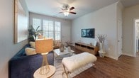 This single-floor residence offers a thoughtfully designed layout that balances modern finishes with comfortable living. The kitchen is a standout feature, showcasing rich dark cabinetry, granite-style countertops, and a full suite of stainless steel appliances including a refrigerator, range, microwave, and dishwasher. Wood-look flooring runs throughout the kitchen, adding warmth to the contemporary aesthetic.

The living area is bright and inviting, benefiting from multiple windows that allow generous natural light to fill the space. A ceiling fan adds both function and character, while wood-look flooring continues the cohesive design. The room offers ample space for relaxed seating and entertainment arrangements.

The bedrooms are carpeted for comfort and feature large windows with views of lush outdoor greenery, including palm trees, creating a serene atmosphere. Each bedroom is well-proportioned with clean, neutral walls.

The residence includes two bathrooms. The primary bathroom features a dual-sink vanity with granite-style countertops, dark cabinetry, and a shower-tub combination. The secondary bathroom mirrors the design quality with a single-sink vanity and a tub-shower unit. Both bathrooms feature wood-look flooring and well-lit vanity mirrors, completing the polished, consistent design found throughout the home.