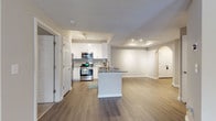 Located in Atlanta, GA, this single-floor residence presents a well-designed open-concept layout that connects the kitchen and living areas seamlessly. The kitchen is a notable highlight, featuring crisp white cabinetry, granite countertops with a subtle blue-gray veining, a subway tile backsplash, and a full suite of stainless steel appliances including a gas range, over-the-range microwave, and refrigerator. A peninsula with matching granite provides additional counter space and doubles as a casual dining area. The living room is generously proportioned, with hardwood-style flooring, a ceiling fan, and a fireplace framed by a clean white surround, lending warmth to the space. Natural light filters in through windows fitted with blinds. An arched doorway adds an architectural touch connecting different areas of the home. The bedroom offers plush carpeting, a ceiling fan, and a window with outdoor views. The bathroom includes wood-look flooring, a granite-topped vanity with white cabinetry, and a shower-tub combination. Hallway areas transition smoothly between rooms, maintaining a cohesive, neutral color palette throughout.