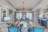 Located on Boulevard de Sevilla in Foley, Alabama, this single-story community clubhouse offers a thoughtfully designed gathering space with a cohesive coastal aesthetic. The main lounge serves as the centerpiece, featuring tray ceilings, crown molding, and an elegant chandelier that anchors the room. Vibrant teal accent chairs, a neutral sofa, and a herringbone-patterned hardwood floor create an inviting and polished atmosphere, while large windows dressed with patterned curtains flood the space with natural light and views of the surrounding grounds.

Adjacent to the lounge, a kitchenette with dark cabinetry, stainless steel appliances, and a casual dining nook provides a convenient space for residents to gather. A dedicated business center features high ceilings, globe pendant lighting, computer workstations, and flexible seating arrangements, making it ideal for remote work or study.

The fitness center is generously sized, equipped with multiple treadmills, ellipticals, a multi-station weight machine, and balance equipment, all beneath vaulted ceilings with ceiling fans and ample window light. An outdoor covered pavilion rounds out the amenities, offering a full kitchenette, wicker lounge seating, a dining table, and cathedral-style coffered ceilings — perfect for entertaining with views of the surrounding landscape.