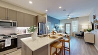 Located at 50 N McQueen Rd in Gilbert, AZ, this well-appointed 2-bedroom, 2-bathroom residence offers a thoughtfully designed single-floor layout. The open-concept kitchen flows seamlessly into the living area and features taupe shaker-style cabinetry, quartz countertops, under-cabinet lighting, stainless steel appliances, and a large island with bar seating—ideal for both everyday cooking and entertaining. Light wood-style flooring runs throughout the main living areas, adding warmth and continuity.

The living room is bright and inviting, with natural light streaming through large windows and a sliding glass door that opens to the outdoors. A ceiling fan adds comfort, and the space offers ample room for relaxed living.

The spacious primary bedroom includes plush carpet, large windows with blinds and curtains, and direct access to a private bathroom featuring a dual-sink vanity with quartz counters, dark cabinetry, an illuminated mirror, and wood-look flooring. A generously sized walk-in closet with built-in shelving and double hanging rods provides excellent storage. The second bedroom is equally comfortable and well-lit. The second bathroom offers a tub-shower combination with tile surround. Both closets are well-organized, completing this efficient and stylish home.