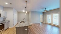 This well-appointed 2-bedroom, 2-bathroom apartment at 2406 Green Valley Rd in New Albany, Indiana offers a thoughtfully designed single-floor layout. The open-concept living area features light hardwood-style flooring and a ceiling fan, with French doors that invite natural light and outdoor views. The kitchen is a standout space, showcasing a granite-topped island with a stainless steel sink and stylish pendant lighting, complemented by gray cabinetry, granite countertops, and a full suite of stainless steel appliances including a refrigerator, range, and microwave. The kitchen flows seamlessly into the dining and living areas, creating an ideal space for everyday living and entertaining. Both bedrooms offer neutral tones, hardwood-style flooring, and windows with outdoor views, while the primary bedroom provides a comfortable and spacious retreat. Four closets throughout the unit ensure ample storage. The bathrooms feature granite-topped vanities and a tub/shower combination. A dedicated laundry area adds everyday convenience, rounding out this functional and modern living space.
