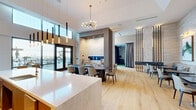 Located in the heart of Buckhead at 340 E Paces Ferry Rd NE, Atlanta, GA, this elegantly designed amenity space offers a seamless blend of style and functionality across a single, generously proportioned floor. The open-concept layout is anchored by soaring ceilings that amplify the sense of space throughout.

The fully equipped kitchen serves as a central focal point, featuring a large waterfall-edge island with seating, warm wood cabinetry, gold tile backsplash, and pendant lighting. Adjacent dining and lounge areas are furnished with curated seating arrangements, accented by a sleek linear fireplace set within a dramatic marble-clad wall and vibrant botanical artwork.

Natural light pours in through expansive floor-to-ceiling windows, offering direct views of an outdoor rooftop pool and lounge deck. A striking marble accent wall, live tropical plants, and light hardwood flooring contribute to the space's refined, contemporary ambiance.

A dedicated sports simulation room rounds out the amenities, complete with a golf and multi-sport simulator, turf flooring, and equipment storage — a standout feature for recreation enthusiasts.

Throughout, the design palette of marble, wood tones, and soft neutrals creates a cohesive, upscale atmosphere suited for both social gatherings and relaxed everyday use.