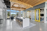 Located at 2315 South 11th Avenue in Bozeman, Montana, this thoughtfully designed collaborative space offers a dynamic environment for studying, gathering, and focused work. The single-floor layout spans a generous footprint, combining open-plan areas with enclosed private rooms to accommodate a variety of needs.

Architecturally, the space is distinguished by warm, natural wood plank ceilings with exposed structural beams and visible ductwork, creating an industrial-yet-inviting aesthetic. Polished concrete floors run throughout, providing a clean, durable surface that reflects the abundant natural light pouring in through the expansive floor-to-ceiling windows lining the perimeter walls.

The open lounge area features a central high-top bar island with bar stools, modular seating arrangements, and individual café-style tables with blue upholstered chairs — ideal for both solo work and small group collaboration. Bold, abstract graphic murals adorn the walls, adding artistic energy to the space, while motivational text is displayed prominently near the ceiling.

Enclosed private study rooms are accessible via striking yellow-framed sliding barn doors with frosted glass panels featuring artistic designs, offering visual privacy while maintaining a sense of openness. Each room is equipped with a display screen and collaborative seating. The overall ambiance is bright, modern, and energizing, designed to stimulate productivity and creativity.