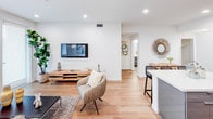 Located at 8740 S La Tijera Blvd in Los Angeles, this single-floor unit presents a contemporary design with a clean, neutral palette throughout. The open-plan living area features light wood flooring, recessed lighting, and a seamless flow into the kitchen and dining space, creating a bright and cohesive environment.

The kitchen is outfitted with sleek, dark gray high-gloss cabinetry, white quartz countertops, and a full suite of stainless steel appliances, including a range, microwave, dishwasher, and refrigerator. A kitchen island with bar seating provides an additional casual dining option. A dedicated laundry closet with a stacked washer and dryer unit adds practical convenience.

The bedrooms are carpeted and well-proportioned, with one featuring an en-suite bathroom and a generously sized walk-in closet. Both bathrooms are finished with gray tile flooring, modern floating vanities, white quartz countertops, and large mirrors. One bathroom includes a shower-tub combination, while the other offers a walk-in shower setup. The overall design is cohesive and modern, emphasizing functionality and understated elegance throughout.