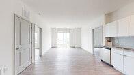 Located at 27 S King Street in Hampton, Virginia, this single-floor residence offers a bright, contemporary living experience defined by clean lines and modern finishes throughout. The open-concept living area is bathed in natural light, showcasing light wood-style flooring, crisp white walls, and a sliding glass door that leads to a private balcony with open outdoor views of the surrounding cityscape.

The kitchen is well-appointed with white shaker-style cabinetry extending to the ceiling, granite countertops, a classic subway tile backsplash, and a full suite of stainless steel appliances including a side-by-side refrigerator with ice and water dispenser, electric range, built-in microwave, and dishwasher.

The bedroom features a ceiling fan, large window framing city views, and the same warm wood-style flooring found throughout the unit. Additional rooms provide flexible space connected via stylish panel doors.

The bathrooms are finished with granite-top white vanities, light tile flooring, and full soaking tub/shower combinations. One bathroom features a backlit LED vanity mirror and modern gold-tone fixtures, adding a refined touch. Overall, the space delivers a clean, modern aesthetic with quality finishes in a well-connected Hampton location.