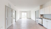 Located at 27 S King Street in Hampton, Virginia, this single-floor residence offers a bright, contemporary living experience defined by clean lines and modern finishes throughout. The open-concept living area is bathed in natural light, showcasing light wood-style flooring, crisp white walls, and a sliding glass door that leads to a private balcony with open outdoor views of the surrounding cityscape.

The kitchen is well-appointed with white shaker-style cabinetry extending to the ceiling, granite countertops, a classic subway tile backsplash, and a full suite of stainless steel appliances including a side-by-side refrigerator with ice and water dispenser, electric range, built-in microwave, and dishwasher.

The bedroom features a ceiling fan, large window framing city views, and the same warm wood-style flooring found throughout the unit. Additional rooms provide flexible space connected via stylish panel doors.

The bathrooms are finished with granite-top white vanities, light tile flooring, and full soaking tub/shower combinations. One bathroom features a backlit LED vanity mirror and modern gold-tone fixtures, adding a refined touch. Overall, the space delivers a clean, modern aesthetic with quality finishes in a well-connected Hampton location.