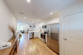 Located at 1 Pleasant St, Unit 302 in Cohasset, MA, this well-appointed one-bedroom, one-bathroom residence offers a thoughtfully designed layout with a bright, cohesive aesthetic throughout. Warm hardwood flooring flows seamlessly across every room, lending a sense of continuity and natural warmth to the entire space.

The open-concept kitchen and living area forms the heart of the unit. The kitchen is outfitted with crisp white shaker-style cabinetry, light quartz countertops, and a full suite of stainless steel appliances, including a side-by-side refrigerator, electric range, built-in microwave, and dishwasher. Recessed lighting and a pendant fixture provide ample illumination. The living area benefits from vaulted ceilings and windows that draw in generous natural light and offer pleasant outdoor views of the surrounding neighborhood.

The bedroom is a calm, restful retreat featuring vaulted ceilings, a large window framing green treetop views, a closet, and a coastal-inspired ambiance enhanced by soft, neutral tones. The bathroom is clean and modern, appointed with white cabinetry, a single vanity with a large mirror, and light tile flooring, creating a spa-like atmosphere. The overall design of the unit balances functional efficiency with an inviting, airy character well-suited to comfortable everyday living.