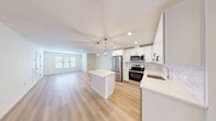 Located at 6 Arbutus Path in Mount Sinai, NY, this well-appointed two-story residence offers a thoughtfully designed layout across its main living floor. The heart of the home is a bright, open-concept space combining the living room, dining area, and kitchen — all finished with light hardwood flooring that enhances the airy, modern aesthetic. The kitchen is a standout feature, showcasing white shaker cabinetry, a marble-style tile backsplash, quartz countertops, a central island, stainless steel appliances including a French door refrigerator and electric range, and stylish pendant lighting overhead. The generously sized bedroom is carpeted for comfort and features a sliding glass door that opens directly onto a private balcony with outdoor views. A custom walk-in closet with rich wood shelving and dual hanging rods provides excellent storage. The full bathroom is elegantly finished with marble-look tile flooring, a white vanity, and an LED-backlit mirror alongside a tiled shower. Additional conveniences include a dedicated laundry area, a utility room, and multiple closets throughout. The clean, neutral palette and modern finishes throughout create a cohesive and inviting living environment.