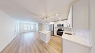Located at 6 Arbutus Path in Mount Sinai, NY, this well-appointed two-story residence offers a thoughtfully designed layout across its main living floor. The heart of the home is a bright, open-concept space combining the living room, dining area, and kitchen — all finished with light hardwood flooring that enhances the airy, modern aesthetic. The kitchen is a standout feature, showcasing white shaker cabinetry, a marble-style tile backsplash, quartz countertops, a central island, stainless steel appliances including a French door refrigerator and electric range, and stylish pendant lighting overhead. The generously sized bedroom is carpeted for comfort and features a sliding glass door that opens directly onto a private balcony with outdoor views. A custom walk-in closet with rich wood shelving and dual hanging rods provides excellent storage. The full bathroom is elegantly finished with marble-look tile flooring, a white vanity, and an LED-backlit mirror alongside a tiled shower. Additional conveniences include a dedicated laundry area, a utility room, and multiple closets throughout. The clean, neutral palette and modern finishes throughout create a cohesive and inviting living environment.