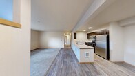 This two-bedroom, two-bathroom residence at Uptown Square in Federal Way, Washington offers a well-designed single-level layout that balances functionality with comfort. The open-concept living and kitchen area serves as the heart of the home, where light wood-style flooring flows seamlessly from the kitchen peninsula into the main living space, which transitions into plush wall-to-wall carpeting. The kitchen is outfitted with dark espresso cabinetry, stainless steel appliances including a refrigerator, range, microwave, and dishwasher, and a light-toned countertop peninsula that provides both prep space and a casual dining option. The living area is bright and open, with natural light filtering in from multiple windows. Both bedrooms are carpeted and feature neutral tones, with natural light provided by windows overlooking greenery. One bedroom includes a built-in closet with a sliding door, while another offers direct exterior door access. The bathrooms are clean and functional, with one featuring a full tub-shower combination, a single vanity with dark cabinetry, and tile-style flooring. A hallway connects the main living areas to the private bedrooms and bathrooms, creating a logical and comfortable flow throughout the residence.