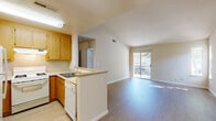 This single-floor residential unit offers a well-organized, open layout that maximizes functionality and natural light. The kitchen is equipped with warm honey-toned wood cabinetry, a gas range, a dishwasher, a refrigerator, and a double sink, all finished with light countertops. A peninsula-style counter connects the kitchen to the living area, creating a seamless open-concept flow ideal for everyday living.

The living area features durable light-toned laminate flooring and vaulted ceilings that lend a sense of height and openness. A sliding glass door leads directly to a private balcony, allowing ample natural light to fill the space and providing views of the surrounding outdoor environment. A ceiling fan is also present, adding both comfort and functionality to the area.

The bedroom is carpeted and generously proportioned, with its own sliding glass door providing additional outdoor access and natural light. The neutral tones throughout the unit create a calm, cohesive aesthetic.

The bathroom features light wood cabinetry, a countertop vanity, and light-toned flooring, maintaining the clean and consistent design language found throughout the home. Additional storage is accessible via a hallway closet. Overall, the unit presents a practical and comfortable living environment with a bright, airy character.