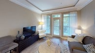 Located at 2211 Parklake Dr NE in Atlanta's vibrant 30345 corridor, this single-floor residence combines modern finishes with a thoughtfully designed open-concept layout. The living room serves as the heart of the space, showcasing a tray ceiling with crown molding detail, warm hardwood-style flooring, and oversized French doors that flood the room with natural light and open to a private outdoor area with lush greenery views. The kitchen is a standout feature, outfitted with rich dark walnut cabinetry extending to the ceiling, granite countertops, stainless steel appliances including a range, microwave, and refrigerator, and a peninsula with a double basin sink — ideal for both everyday cooking and entertaining. Track lighting and crown molding add a polished finish throughout. The bedroom offers a serene retreat with plush carpeting, neutral warm-toned walls, and ample room for a full furniture arrangement. Architectural details such as crown molding, tray ceilings, and clean white panel doors are consistent throughout, lending a cohesive and refined aesthetic. The overall ambiance is warm, contemporary, and well-appointed, making this residence a comfortable and visually appealing space in the heart of Atlanta.