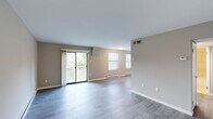 Located at 955 Easton Rd in Warrington, PA, this two-floor residence offers three bedrooms and one bathroom with a practical, well-organized layout. The main living area features a combined kitchen and living room with light gray luxury vinyl plank flooring and neutral-toned walls. The kitchen is equipped with two-tone cabinetry — dark lower cabinets paired with white uppers — stainless steel appliances including a refrigerator, gas range, and microwave, plus light countertops and a window overlooking the greenery outside. The living room opens directly onto a private balcony through a sliding glass door, offering pleasant views of the landscaped grounds and surrounding trees. The three bedrooms are carpeted in warm, neutral tones and feature soft gray walls, baseboard heating, and panel-style doors. The spacious primary bedroom includes a built-in closet with sliding doors. The full bathroom is finished with large-format, light-toned wall tile surrounding a clean white soaking tub. A hallway connects the bedrooms and bathroom on the upper floor, with a staircase providing access between levels. Baseboard heating is present throughout the residence, and the overall aesthetic is clean, neutral, and move-in ready.