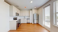 Located in Roanoke, TX, this one-bedroom, one-bathroom unit offers a thoughtfully designed layout across a single floor. Warm hardwood-style flooring runs throughout the open living areas, creating a bright and cohesive feel. The kitchen is a standout feature, outfitted with crisp white cabinetry, a full suite of stainless steel appliances including an electric range, built-in microwave, dishwasher, full-size refrigerator, and a dedicated wine cooler — all centered around a clean white tile backsplash. The open layout connects the kitchen seamlessly to the living area, enhancing the sense of space. The bedroom is a well-proportioned, peaceful retreat with a ceiling fan, natural light from a large window with views of the surrounding area, and direct access to a closet. The bathroom features a soaking tub with a tiled surround in neutral stone-like tones, accented with brushed nickel and gold hardware for a polished finish. Additional conveniences include a dedicated laundry area, a private balcony, and an entrance foyer. Clean white walls and recessed lighting lend the space a modern, move-in-ready aesthetic throughout.