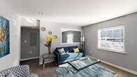 Located at 514 Bridge Ave in Forest Park, Georgia, this single-floor residence offers a thoughtfully designed layout with modern finishes and a cohesive gray-toned color palette throughout. The living room serves as the heart of the home, featuring dark hardwood-style flooring, large windows fitted with blinds that invite natural light, and a distinctive interior pass-through window that visually connects spaces and adds architectural interest. The kitchen is well-equipped with white shaker-style cabinetry, granite-look countertops, a white subway tile backsplash, and stainless steel appliances including a range, microwave, and dishwasher. A dedicated dining area adjacent to the kitchen provides a cozy space for meals, illuminated by a window above. The bedroom is a comfortable retreat with a ceiling fan, a window, and dark accent walls that create a calm atmosphere. The bathroom features a white vanity with granite-style countertops, dark hardwood-style flooring, and a window for natural ventilation. Throughout the home, consistent flooring, neutral gray walls, and clean white trim create a polished, move-in-ready aesthetic that balances comfort and modern style.