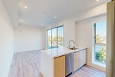 Located at 139 S Occidental Blvd in the heart of Los Angeles, this modern 2-bedroom, 2-bathroom unit offers a thoughtfully designed open-concept layout filled with natural light. The combined kitchen and living area serves as the centerpiece of the home, featuring light hardwood-style flooring, recessed lighting, and expansive floor-to-ceiling sliding glass doors that frame stunning views of the Los Angeles skyline and surrounding neighborhood. The kitchen is appointed with a sleek white quartz peninsula, stainless steel appliances including a refrigerator, electric range, and microwave, as well as warm wood-toned cabinetry for a contemporary aesthetic. A bright hallway with the same hardwood-style flooring connects the main living area to the bedrooms, which are carpeted for comfort. The bedrooms are generously proportioned, with the primary bedroom featuring a large built-in closet with ample shelving and hanging space. Both bathrooms are finished with clean white tile, light wood vanities, and sliding glass shower-tub enclosures, maintaining the home's modern and cohesive design. The overall ambiance is fresh, bright, and contemporary, ideal for urban living in Los Angeles.