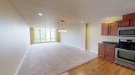 Located on the third floor at 1142 Fawcett Ave in Tacoma, WA, Unit 309 is a thoughtfully designed residence that combines modern finishes with a functional, open layout. The heart of the unit is the expansive open-concept living and kitchen area, where warm hardwood flooring in the kitchen transitions seamlessly into plush wall-to-wall carpeting in the living space. Large windows along one wall flood the living area with abundant natural light, creating a bright and welcoming atmosphere. A stylish pendant light fixture serves as a central focal point above the shared living and dining space, complemented by recessed lighting throughout.

The kitchen is well-equipped, featuring rich wood cabinetry, striking dark granite countertops, a double-basin sink, and a full suite of stainless steel appliances including a gas range, over-the-range microwave, dishwasher, and refrigerator — providing both style and practicality.

The bedroom is a comfortable, carpeted retreat with a closet and a dedicated electrical panel. The unit also includes a full bathroom finished with tile flooring, wood vanity cabinetry, a wide mirror, and a tub/shower combination. A carpeted hallway with wall sconce lighting connects the rooms, lending the unit a cohesive and polished feel throughout.