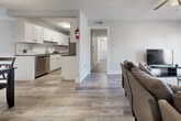 This 2-bedroom, 1.5-bathroom unit offers a thoughtfully designed single-floor layout with a clean, contemporary aesthetic throughout. The open-concept living and dining area provides a welcoming common space anchored by light wood-style flooring, neutral walls, and a ceiling fan overhead. The dining area is defined by a stylish overhead pendant light and comfortably accommodates a four-seat dining set. The galley-style kitchen is a standout feature, equipped with a full suite of stainless steel appliances including a refrigerator, range, microwave, and dishwasher. White shaker cabinetry, gray quartz-style countertops, and a classic white subway tile backsplash give the kitchen a modern, polished look. The primary bedroom is a comfortable retreat featuring a ceiling fan, a window with natural light, and easy access to a hallway closet. The second bedroom also offers a generous sliding-door closet and continues the wood-style flooring found throughout. The bathroom features a white shaker vanity with warm gold fixtures, a taupe countertop, an undermount sink, and elegant marble-style tile flooring. A separate water closet with its own door adds privacy and functionality to the bathroom configuration.