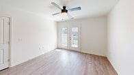 Located at 2036 S Hamilton St in Roanoke Rapids, NC, this single-floor, 2-bedroom, 1-bathroom home offers a well-designed open layout with consistent light wood-style flooring throughout. The combined kitchen and living area serves as the heart of the home, featuring a peninsula with granite-style countertops and a double stainless steel sink, rich taupe cabinetry, black appliances including a gas range and refrigerator, and recessed lighting. The living area flows naturally from the kitchen and includes a ceiling fan and French doors that open to a private outdoor patio, bringing in natural light and easy outdoor access. The primary bedroom is a comfortable, well-lit space with a ceiling fan, a window with natural light, and access to a dedicated walk-in closet outfitted with wire shelving for ample storage. The second bedroom also features a ceiling fan and includes two separate doors — one with a frosted glass panel framed in a distinctive green surround, adding a unique design touch. The full bathroom is spacious and accessible, featuring grab bars and hard-surface flooring. Throughout the home, clean white walls, neutral tones, and consistent flooring create a bright, cohesive living environment.