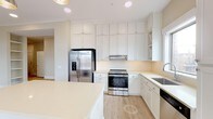Located at 600 Caraway Crossing in Chapel Hill, NC, this single-floor residence offers a clean, contemporary design throughout. The kitchen is a standout feature, outfitted with crisp white shaker-style cabinetry extending to the ceiling, light quartz countertops, a decorative tile backsplash, and a full suite of stainless steel appliances including a gas range, French door refrigerator, and dishwasher. A large central island provides additional prep space, while a window above the sink fills the room with natural light. The bedrooms are generously sized, finished with plush neutral carpeting and large windows fitted with blinds that bring in ample daylight. The primary bedroom features light hardwood-style flooring, built-in open shelving, crown molding, and a stylish barn-style sliding door leading to an en-suite bath. The primary bathroom is well-appointed with a dual-sink vanity, soaking tub, separate glass-enclosed shower, tile flooring, and direct access to a walk-in closet. A secondary full bathroom mirrors the home's clean aesthetic with a tub-shower combination and tile flooring. A dedicated laundry area accommodates a full-size side-by-side washer and dryer. Throughout, the home maintains a cohesive, light, and airy palette.