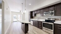 Located at 450 Tenth Avenue in San Diego's vibrant 92101 zip code, this 2-bedroom, 1-bathroom residence offers a thoughtfully designed single-floor layout with contemporary finishes throughout. The open-concept living, dining, and kitchen area serves as the heart of the home, anchored by a sleek kitchen featuring rich dark-espresso cabinetry, light quartz countertops, a tiled backsplash, stainless steel appliances, and a curved breakfast bar illuminated by pendant lighting. Light wood-style flooring flows seamlessly throughout the space, complementing the neutral, warm-toned walls and creating a bright, cohesive aesthetic. A ceiling fan in the living area adds comfort, while sliding glass doors open to an outdoor balcony with views of the surrounding urban courtyard. The bedrooms are well-proportioned, each benefiting from natural light through large windows and ceiling fans overhead. The bathroom is clean and modern, finished with large-format tile in the tub/shower surround and on the floor. A dedicated laundry area, multiple closets, and a connecting hallway round out the practical layout. This residence combines efficient urban living with polished, modern design in the heart of San Diego.