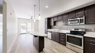 Located at 450 Tenth Avenue in San Diego's vibrant 92101 zip code, this 2-bedroom, 1-bathroom residence offers a thoughtfully designed single-floor layout with contemporary finishes throughout. The open-concept living, dining, and kitchen area serves as the heart of the home, anchored by a sleek kitchen featuring rich dark-espresso cabinetry, light quartz countertops, a tiled backsplash, stainless steel appliances, and a curved breakfast bar illuminated by pendant lighting. Light wood-style flooring flows seamlessly throughout the space, complementing the neutral, warm-toned walls and creating a bright, cohesive aesthetic. A ceiling fan in the living area adds comfort, while sliding glass doors open to an outdoor balcony with views of the surrounding urban courtyard. The bedrooms are well-proportioned, each benefiting from natural light through large windows and ceiling fans overhead. The bathroom is clean and modern, finished with large-format tile in the tub/shower surround and on the floor. A dedicated laundry area, multiple closets, and a connecting hallway round out the practical layout. This residence combines efficient urban living with polished, modern design in the heart of San Diego.