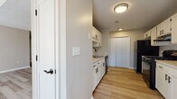 This single-floor residence offers a well-organized layout designed for comfortable everyday living. The living area is a standout space, featuring soaring vaulted ceilings with a textured finish and light hardwood-style flooring that extends throughout the main areas, creating an open and airy atmosphere. A large arched window and additional standard windows allow abundant natural light to fill the space.

The galley-style kitchen is efficiently designed with white cabinetry accented by matte black hardware, light-toned countertops, and black appliances including a gas range with overhead ventilation. A built-in sink, dishwasher, and a full-size refrigerator complete the setup, while light hardwood-style flooring continues underfoot. A pantry closet at the end of the kitchen provides additional storage.

The bedrooms are finished with plush carpeting and feature windows with exterior views, ceiling fans for climate control, and generous closet space. The bathrooms are clean and functional, each equipped with a full tub and shower combo, wood-style flooring, and matte black fixtures and towel bars throughout, maintaining a cohesive design aesthetic across the entire residence.