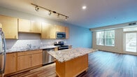Located at 9400 Lexington Avenue North in Circle Pines, MN, this one-bedroom, one-bathroom unit offers a well-organized single-floor layout designed for comfortable everyday living. Rich hardwood-style flooring flows consistently throughout the space, creating a warm and cohesive aesthetic.

The combined kitchen and living room serves as the heart of the unit. The kitchen is well-appointed with light maple cabinetry, granite countertops, a central island for additional prep space, stainless steel appliances including a refrigerator, range, microwave, and dishwasher, and track lighting overhead. The living area benefits from large windows fitted with vertical blinds, allowing generous natural light and views of the surrounding greenery.

The bedroom is a comfortable and well-proportioned space, featuring a large window with outdoor views, adding brightness and a connection to the exterior landscape. A closet provides practical storage, while a hallway connects the rooms efficiently.

The bathroom features a full tub-shower combination, a wood-toned vanity with a white countertop, and clean white finishes throughout. An entry door with a transom window in the living area adds an additional source of natural light, completing this thoughtfully arranged and move-in-ready unit.