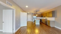 This single-floor residence offers a thoughtfully designed open-concept layout that seamlessly connects the kitchen, dining, and living areas. The kitchen is a standout feature, equipped with warm-toned wood cabinetry, granite countertops, a central island with pendant lighting fashioned from rustic wood and lantern-style fixtures, and a full suite of stainless steel appliances including a refrigerator, range, microwave, and dishwasher. A matte black faucet at the sink adds a contemporary accent. Durable hardwood-style flooring flows throughout the main living areas, complementing the neutral gray walls and crisp white trim.

The living area is generously proportioned, featuring a ceiling fan and a sliding glass door that opens to a balcony, allowing natural light to fill the space. Bedrooms are carpeted for comfort and include ceiling fans and closets, with one bedroom offering direct access to a private bathroom. Bathrooms are finished with granite-topped wood vanities, illuminated mirrors, and hardwood-style flooring. One full bathroom includes a tub-shower combination. A dedicated laundry area houses a full-size Samsung washer and dryer, adding everyday convenience to this well-appointed residence.