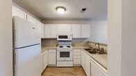 Located at 2510 Atlantic Palms Ln in North Charleston, SC, this single-floor, one-bedroom, one-bathroom residence offers a well-organized and functional layout. The kitchen is a standout feature, appointed with crisp white cabinetry extending to the ceiling for generous storage, light-toned countertops, white appliances including a refrigerator, electric range with over-the-range microwave, and a dishwasher. Wood-style flooring runs throughout the kitchen, which opens to the living area via a breakfast bar counter, creating a connected and social atmosphere. The living room is spacious and carpeted, with neutral walls, textured ceilings, and large windows paired with a glass door that invite abundant natural light and provide outdoor views. The bedroom is a comfortable, well-proportioned retreat featuring carpet flooring, a ceiling fan with light fixture, a window with exterior views, and a built-in desk area. A six-panel closet door leads to additional storage. The bathroom includes a full tub/shower combination and wood-style flooring, maintaining a clean, neutral aesthetic. Throughout the residence, a consistent warm beige palette and textured ceilings contribute to a cohesive, welcoming ambiance.