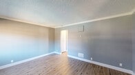 Located at 13495 Bancroft Ave in San Leandro, CA, this one-bedroom, one-bathroom unit offers a well-organized single-floor layout designed for efficient, comfortable living. Throughout the space, cool-toned gray walls, white baseboards, and crown molding create a clean, cohesive aesthetic complemented by textured ceilings.

The combined kitchen and living area provides an open feel, with the living space featuring light wood-look vinyl flooring that continues through the hallway. The kitchen is equipped with white cabinetry, ample upper and lower storage, a stainless steel sink, and white appliances including a range and built-in microwave.

The generously sized bedroom is carpeted for comfort and stands out with a sliding glass door that opens to a private balcony with outdoor views, filling the room with natural light. Mirrored sliding closet doors add depth and practicality to the space.

The full bathroom features a tub-shower combination with tiled surround, a white vanity with a stone-look countertop, a large mirror, and a window for natural ventilation. Wood-look flooring carries through the bathroom, maintaining visual consistency.

A hallway connects the main living areas and includes additional closet space, contributing to the unit's overall storage capacity. The layout is compact yet thoughtfully arranged for day-to-day functionality.
