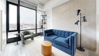 This 30 square meter apartment, located at 2140 Baseline Rd in Ottawa, maximizes space efficiency with its thoughtful layout. The single-floor unit comprises a bedroom, bathroom, kitchen, living room, and hallway. The living area is the heart of the home, boasting floor-to-ceiling windows that flood the space with natural light and provide stunning city views. A sleek blue sofa, contemporary artwork, and strategically placed plants create a modern, inviting atmosphere.

The 9 square meter bedroom features a large, built-in wardrobe and a comfortable bed, with an abstract art piece adding a touch of sophistication. The kitchen, while compact, is well-equipped with stainless steel appliances and ample storage in its crisp white cabinetry. Light wood flooring throughout the apartment adds warmth and continuity.

The bathroom, though not spacious, is designed with clean lines and a minimalist aesthetic, featuring white fixtures and surfaces that contribute to a sense of openness. Despite its modest size, this apartment offers a harmonious blend of style and functionality, ideal for urban living in the heart of Ottawa.