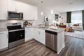 Located in Huntsville, Alabama, this single-floor residence offers a thoughtfully designed open-concept layout that seamlessly connects the kitchen, dining, and living areas. The kitchen is a standout feature, outfitted with crisp white shaker cabinetry, granite countertops, a subway tile backsplash, and a full suite of stainless steel appliances including a refrigerator, range, and microwave. A central island with bar seating and pendant lighting serves as both a functional workspace and a natural gathering point. Wood-look flooring flows consistently throughout the space, adding warmth and continuity. The living area is bright and welcoming, benefiting from large windows that allow generous natural light to fill the room. The bedroom is a comfortable retreat featuring a ceiling fan, a spacious double closet, and an accent wall that adds a distinct sense of character. The bathroom is finished in clean whites with wood-look flooring, offering a tub-shower combination and granite-topped vanity. Overall, the space presents a modern, cohesive aesthetic with neutral tones and contemporary fixtures, making it a well-equipped and visually appealing residence in the Constellation Place community of Huntsville.