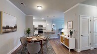 This single-floor residence in Pittsboro, North Carolina, offers a thoughtfully designed open-concept layout that seamlessly connects the kitchen, dining, and living areas. The kitchen is a functional centerpiece, featuring white shaker cabinetry, granite countertops, a tile backsplash, stainless steel appliances, and a large island with an integrated sink and bar seating — ideal for both cooking and casual dining. Pendant lighting above the island adds a polished touch, while recessed lighting and crown molding detail the ceilings throughout the main living areas.

The dining area accommodates a full-sized table and flows naturally into a comfortable living room, which benefits from natural light via window treatments. A welcoming entryway includes a granite-topped bench shelf and a wood-framed mirror, providing a practical transition space.

The bedrooms offer plush carpeting, ceiling fans, and natural light through slatted blinds. The bathroom features a granite vanity with a dark cabinet base, tile flooring, and a shower-tub combination. Hardwood-style flooring runs through the main living spaces, tying the design together with a warm, cohesive aesthetic throughout the home.
