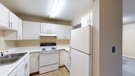This single-floor unit at 4128 W Michigan Ave in Kalamazoo, Michigan offers a practical and straightforward layout across several well-defined spaces. The kitchen is equipped with white cabinetry, ample counter space, a coil-burner electric range, and a full-size refrigerator, all set against neutral-toned walls and tile flooring. An under-cabinet range hood adds functional ventilation above the stove.

The living area features soft gray carpeting and a sliding glass door fitted with vertical blinds, providing direct access to a balcony and allowing natural light and outdoor views to filter into the space. Additional carpeted rooms serve as bedrooms, with one featuring two windows that bring in natural light and another offering a built-in closet with a rod and shelf for organized storage.

The unit includes two bathrooms. The first is a full bath with a vanity, white cabinetry, a lighted mirror, and a tub-shower combination set on tile flooring. The second is a three-quarter bath featuring a standing shower, toilet, and wood-look flooring. Textured ceilings are present throughout, contributing to a consistent interior aesthetic across the unit.