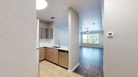 This well-appointed one-bedroom, one-bathroom residence in Orlando, Florida offers a thoughtfully designed layout across a single floor. The open-concept living and kitchen area is bright and welcoming, featuring wood-look plank flooring, neutral tones, and crown molding that adds a refined touch. Ceiling fans are present in both the living area and bedroom, promoting year-round comfort. Large windows fitted with blinds allow abundant natural light while providing privacy.

The kitchen is a standout feature, showcasing modern flat-front cabinetry in a warm wood finish, bright white quartz countertops, a stainless steel undermount sink, and a full suite of stainless steel appliances including a refrigerator, range, microwave, and dishwasher. The layout provides ample counter and storage space.

The generously sized bedroom includes a ceiling fan, wood-look flooring, and direct access to a spacious walk-in closet outfitted with wire shelving and hanging rods for excellent organization. The bathroom features a wood-toned vanity with a white countertop, a lighted mirror, tile flooring, and a shower-tub combination. A private balcony off the living area offers views of surrounding greenery and open sky, completing this functional and comfortable Orlando residence.