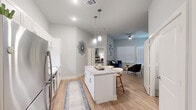 Located at 1619 N Frazier Street in Conroe, Texas, this 1-bedroom, 1-bathroom residence offers a thoughtfully designed single-floor layout that maximizes every square foot of its cozy footprint. The open-concept living and kitchen area serves as the heart of the home, featuring light wood-style flooring that flows seamlessly throughout. The kitchen is outfitted with crisp white shaker cabinets extending to the ceiling, a full suite of stainless steel appliances including a refrigerator, range, microwave, and dishwasher, and a granite-topped island with seating for two, illuminated by stylish pendant lighting. The living room benefits from elevated ceilings, a ceiling fan, and a large window with a glass door that invites natural light and offers access to the outdoors. The bedroom provides a comfortable retreat with plush carpeting and direct access to a spacious walk-in closet featuring multi-tiered shelving and hanging rods for ample storage. The bathroom includes a tiled tub-shower combination with wood-look flooring. A dedicated laundry area houses a full-size washer and dryer, adding everyday convenience to this clean, modern home.
