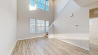 Located at 1951 Integra Dr in West Melbourne, FL, this two-story home offers a thoughtfully designed layout across two floors. The main level features a dramatic two-story living room with soaring ceilings and an abundance of natural light streaming through large windows, including upper transom windows that amplify the sense of openness. Light-toned luxury vinyl plank flooring flows throughout the main living areas, complementing the home's bright, neutral palette. The kitchen is well-appointed with taupe cabinetry, white quartz countertops, a peninsula with pendant lighting, and a full suite of stainless steel appliances, including a refrigerator, dishwasher, and range. The upper level houses the generously sized primary bedroom, complete with plush carpeting, a ceiling fan, a walk-in closet, and direct access to its own private bathroom. The en-suite bath features a dual-sink vanity with white quartz counters, taupe cabinetry, and wood-look tile flooring. A second full bathroom serves the remainder of the home. Additional highlights include a ground-floor carpeted room with exterior door access, multiple hallways for smooth circulation, and a clean, modern aesthetic throughout.