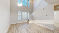 Located at 1951 Integra Dr in West Melbourne, FL, this two-story home offers a thoughtfully designed layout across two floors. The main level features a dramatic two-story living room with soaring ceilings and an abundance of natural light streaming through large windows, including upper transom windows that amplify the sense of openness. Light-toned luxury vinyl plank flooring flows throughout the main living areas, complementing the home's bright, neutral palette. The kitchen is well-appointed with taupe cabinetry, white quartz countertops, a peninsula with pendant lighting, and a full suite of stainless steel appliances, including a refrigerator, dishwasher, and range. The upper level houses the generously sized primary bedroom, complete with plush carpeting, a ceiling fan, a walk-in closet, and direct access to its own private bathroom. The en-suite bath features a dual-sink vanity with white quartz counters, taupe cabinetry, and wood-look tile flooring. A second full bathroom serves the remainder of the home. Additional highlights include a ground-floor carpeted room with exterior door access, multiple hallways for smooth circulation, and a clean, modern aesthetic throughout.