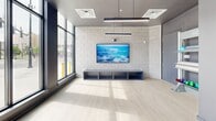 Located at 1143 Main St in Hartford, CT, this modern fitness facility spans a single generously sized floor, offering a well-designed environment for a comprehensive workout experience. The main exercise area is expansive and open, featuring light-colored speckled flooring, structural columns, and an abundance of natural light streaming in through large floor-to-ceiling windows that frame views of the surrounding streetscape. The space is outfitted with a wide array of equipment, including treadmills, stationary bikes, ellipticals, rowing machines, adjustable benches, a full dumbbell rack, cable machines, a functional rig, and hanging heavy bags for boxing and combat training. Geometric linear LED lighting suspended from the ceiling adds a contemporary aesthetic while ensuring excellent illumination throughout. One wall is clad in gray brick, lending an industrial character that contrasts with the clean white ceiling and bright flooring. A separate studio room, enclosed with glass doors and featuring a full-length mirror wall, a mounted flat-screen TV, and light wood-style flooring, provides a versatile space for stretching, personal training, or group classes. The overall design is sleek, modern, and functional, creating a professional-grade fitness environment.
